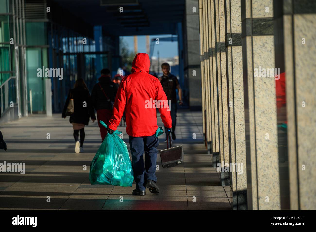 LONDON - November 4, 2020: Street cleaner carries bin bag and dustpan and brush at Canary Wharf Stock Photo