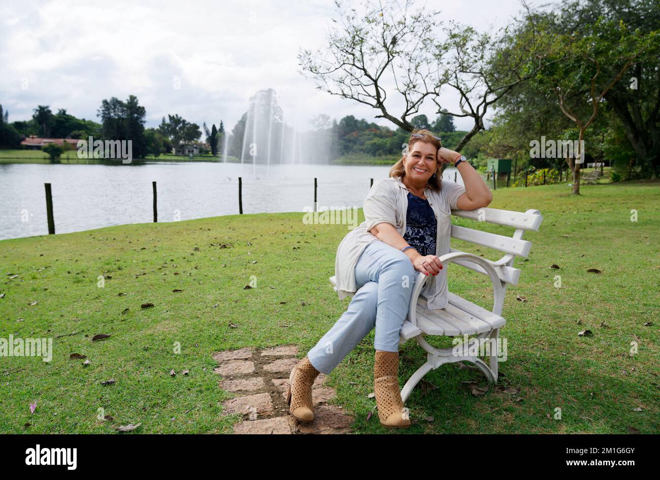 A smiling female sitting in the bench in the park Stock Photo - Alamy