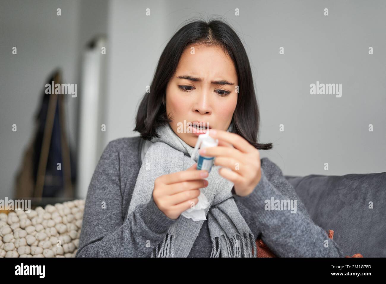 Ill korean woman looking at thermometer with concerned face, catching