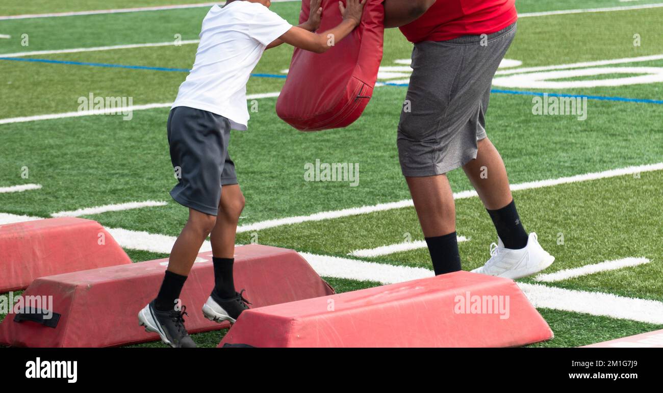 Young boy at football summer camp hitting red pad while running