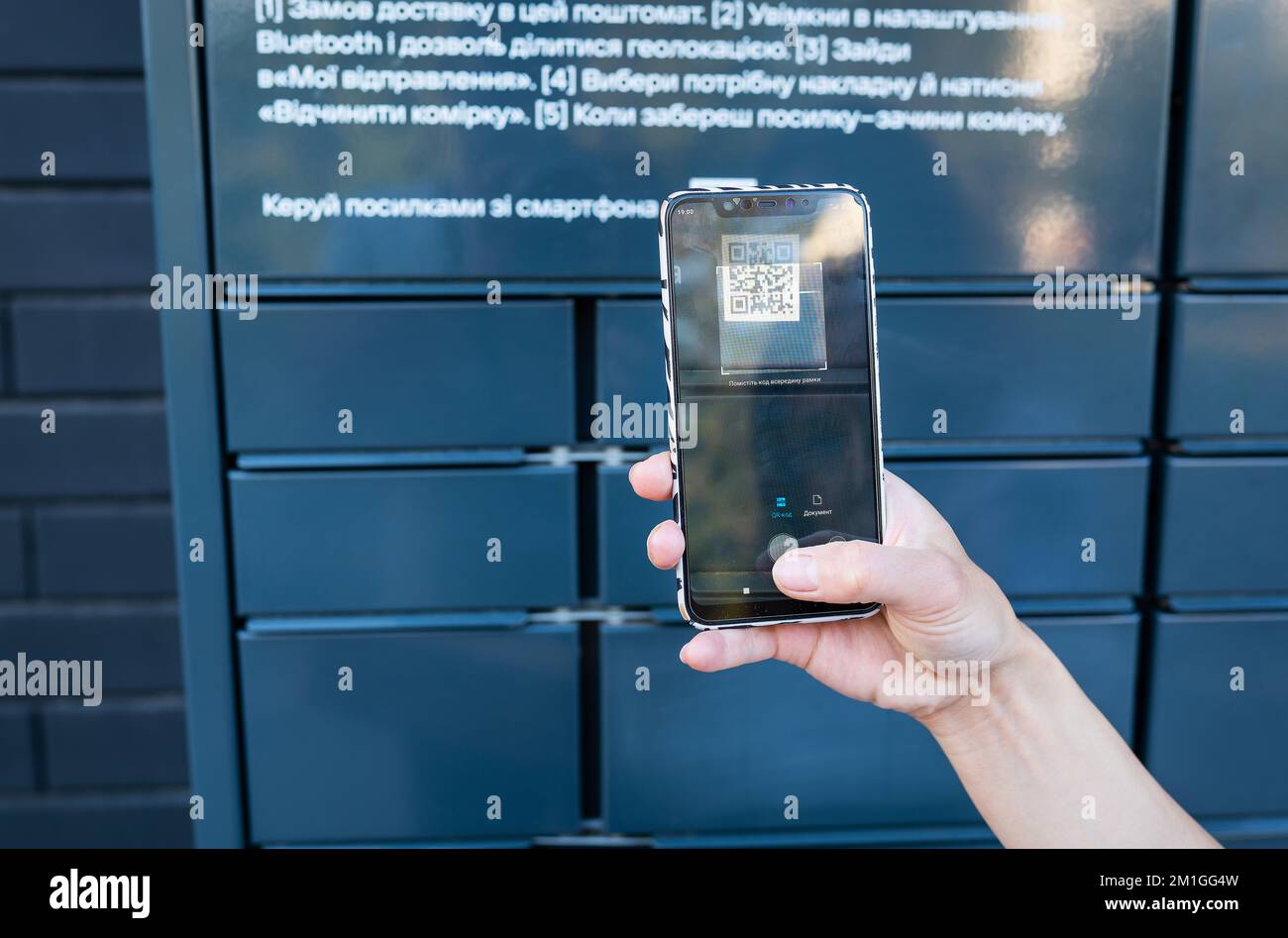 A woman picks up a parcel from a post office by scanning a QR code ...