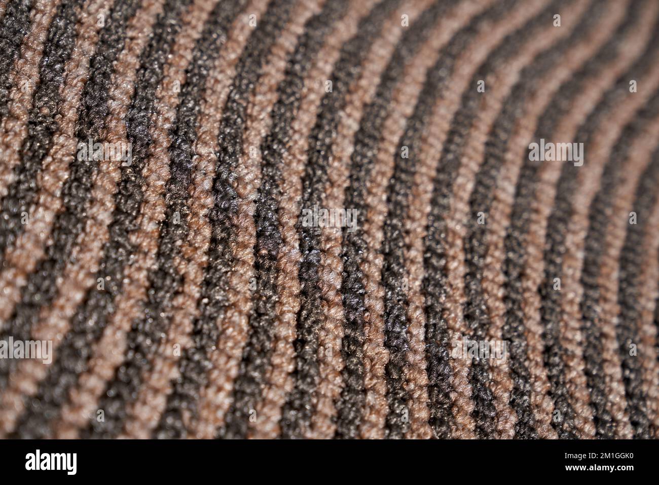 Dark relief carpet texture with asymmetric rows for unusual background. Close up view of strip pattern of synthetic tight wavy rows. Concept of textures and background. Stock Photo