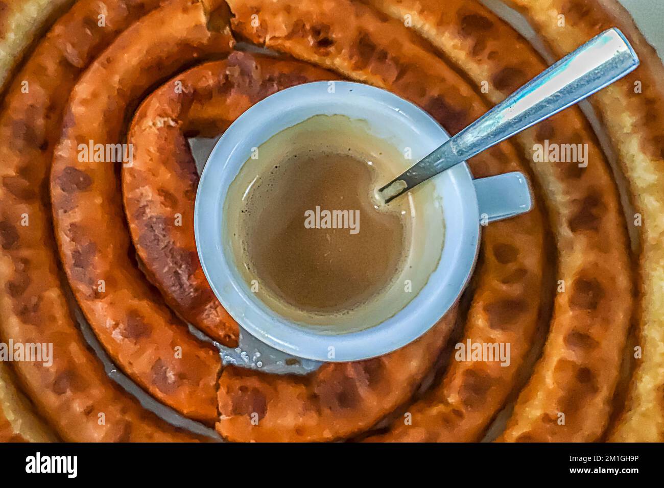 Coffee cut with milk, in the center of a portion of churros Stock Photo
