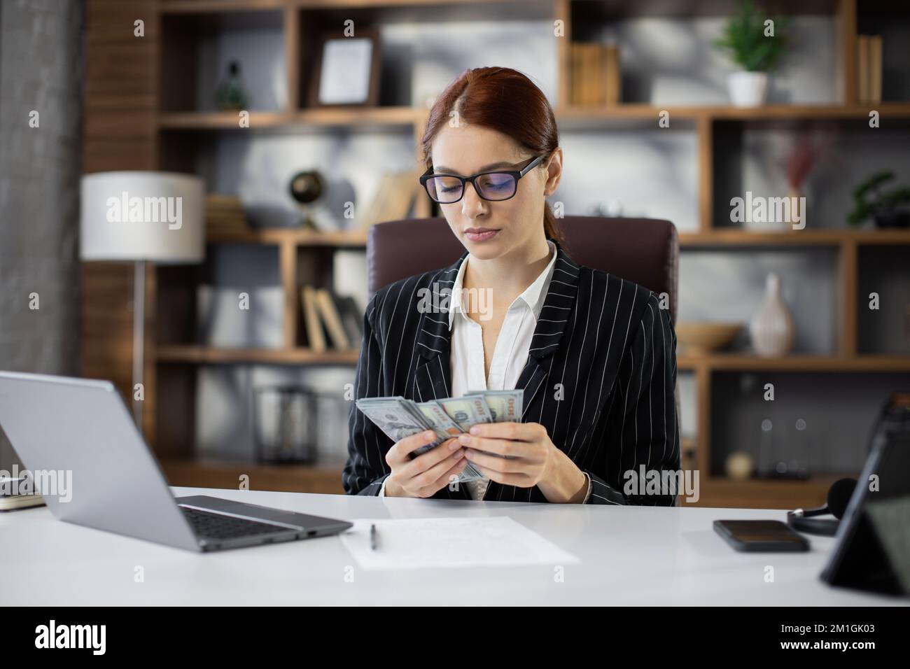 Rich business woman working on laptop counting money cash, calculate