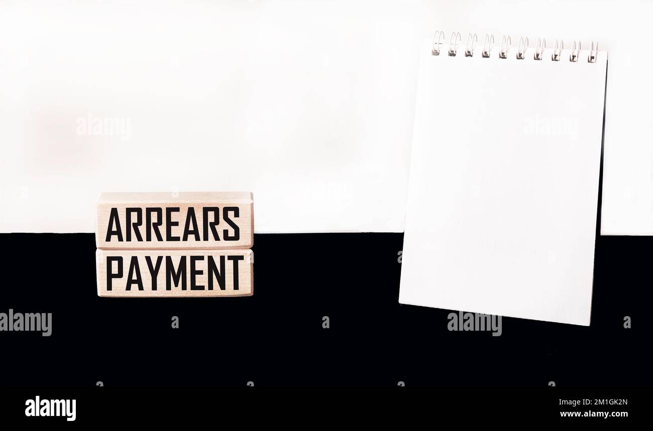 PAYMENT OF DEBT written on wooden blocks on a white and black background with a notepad to write Stock Photo