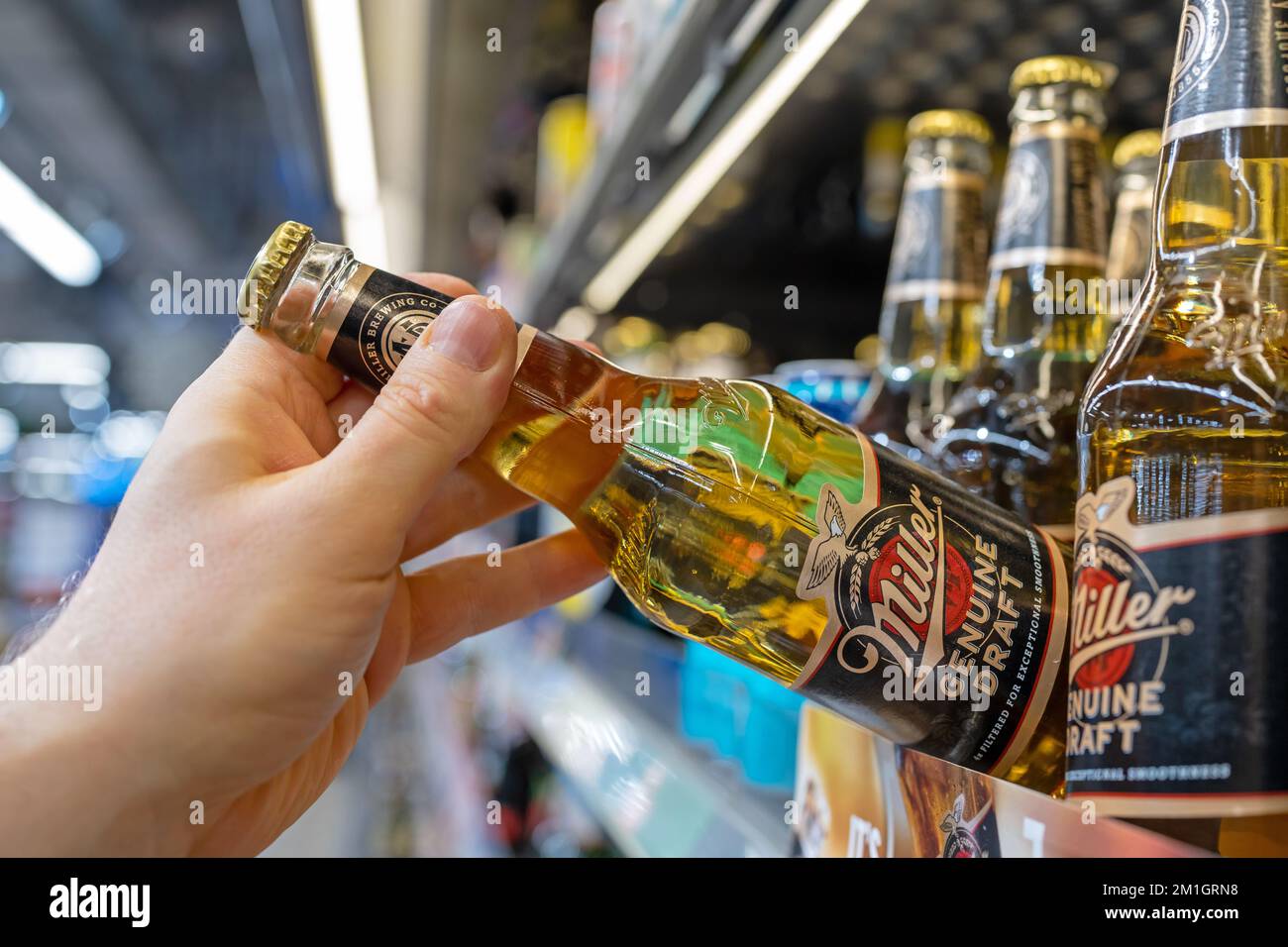 Miller beer bottles on shelves in a supermarket. Buyer takes Miller