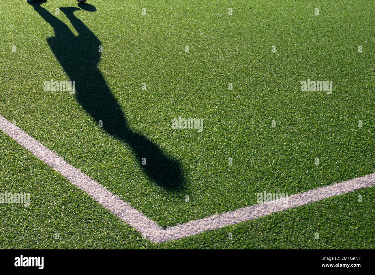 shadow of a young boy playing football with lines of the soccer pitch
