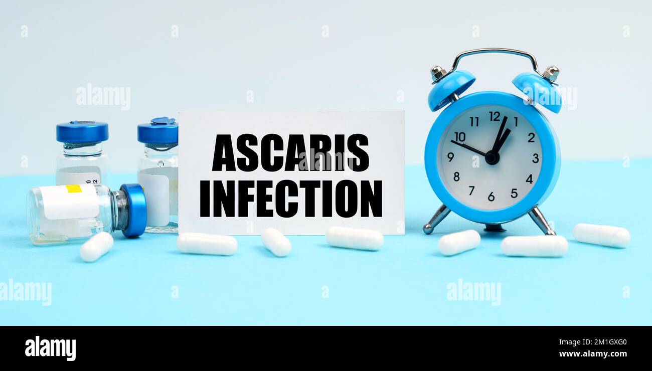 Medicine and health concept. An alarm clock, pills, injections and a card with the inscription - Ascaris Infection Stock Photo