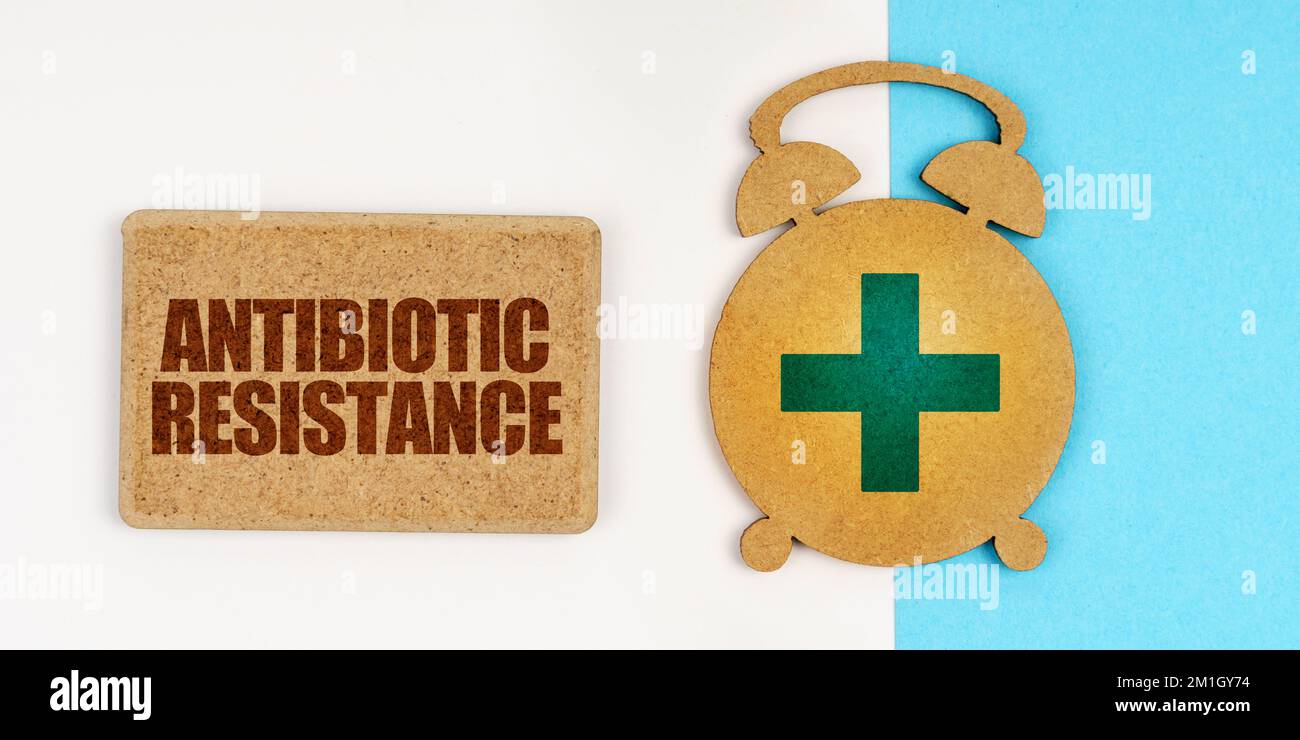 Medicine and health concept. On the white and blue surface are an alarm clock and a sign with the inscription - ANTIBIOTIC RESISTANCE Stock Photo