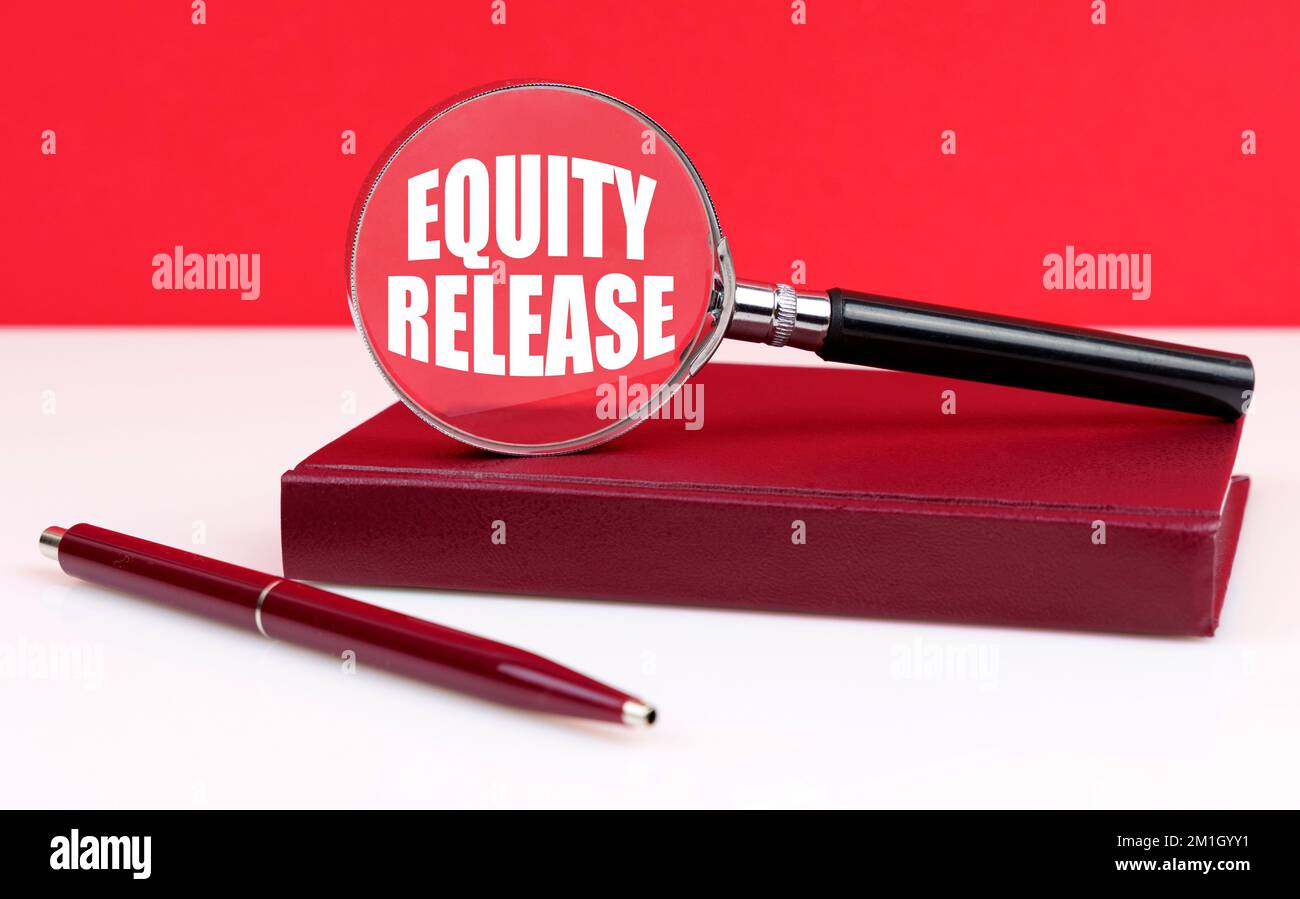 Business and finance concept. On a white and red background, a notebook, a pen and a magnifying glass, inside which the inscription - Equity Release Stock Photo