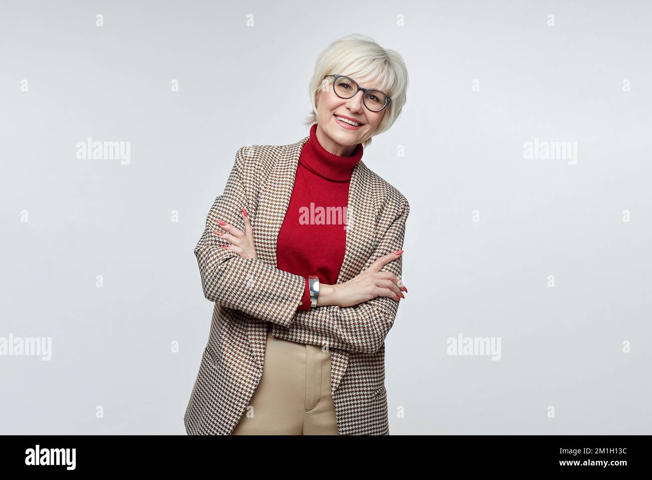 beautiful elderly woman with glasses poses in front of the camera in the studio on a white background. advertising concept of a business woman leader. Stock Photo