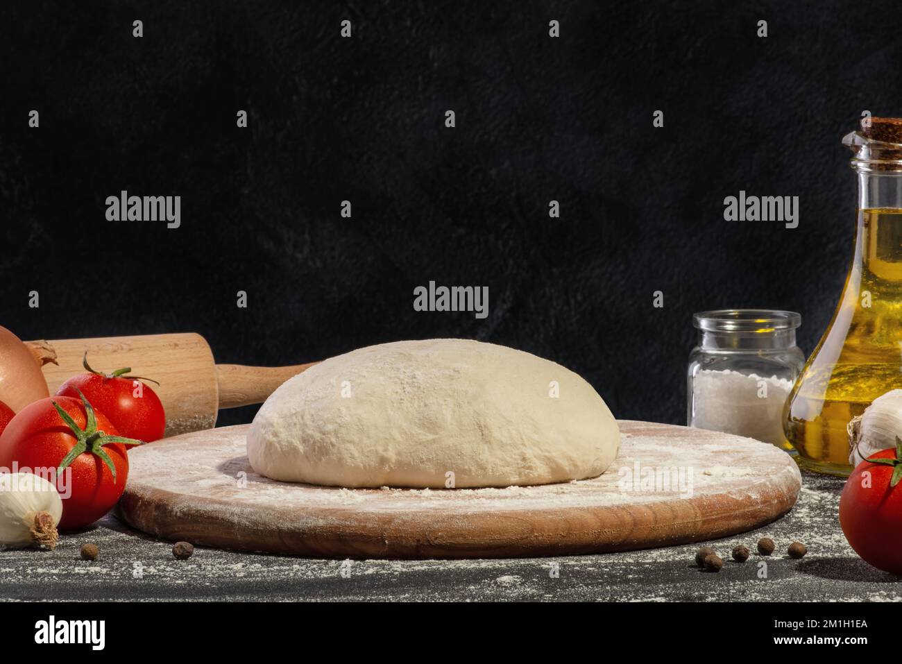 Dough and ingredients for making pizza on a black background. Stock Photo