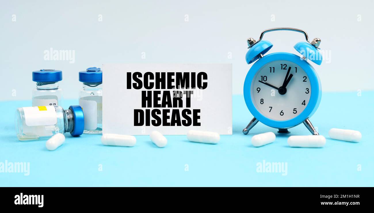 Medicine and health concept. An alarm clock, pills, injections and a card with the inscription - Ischemic Heart Disease Stock Photo