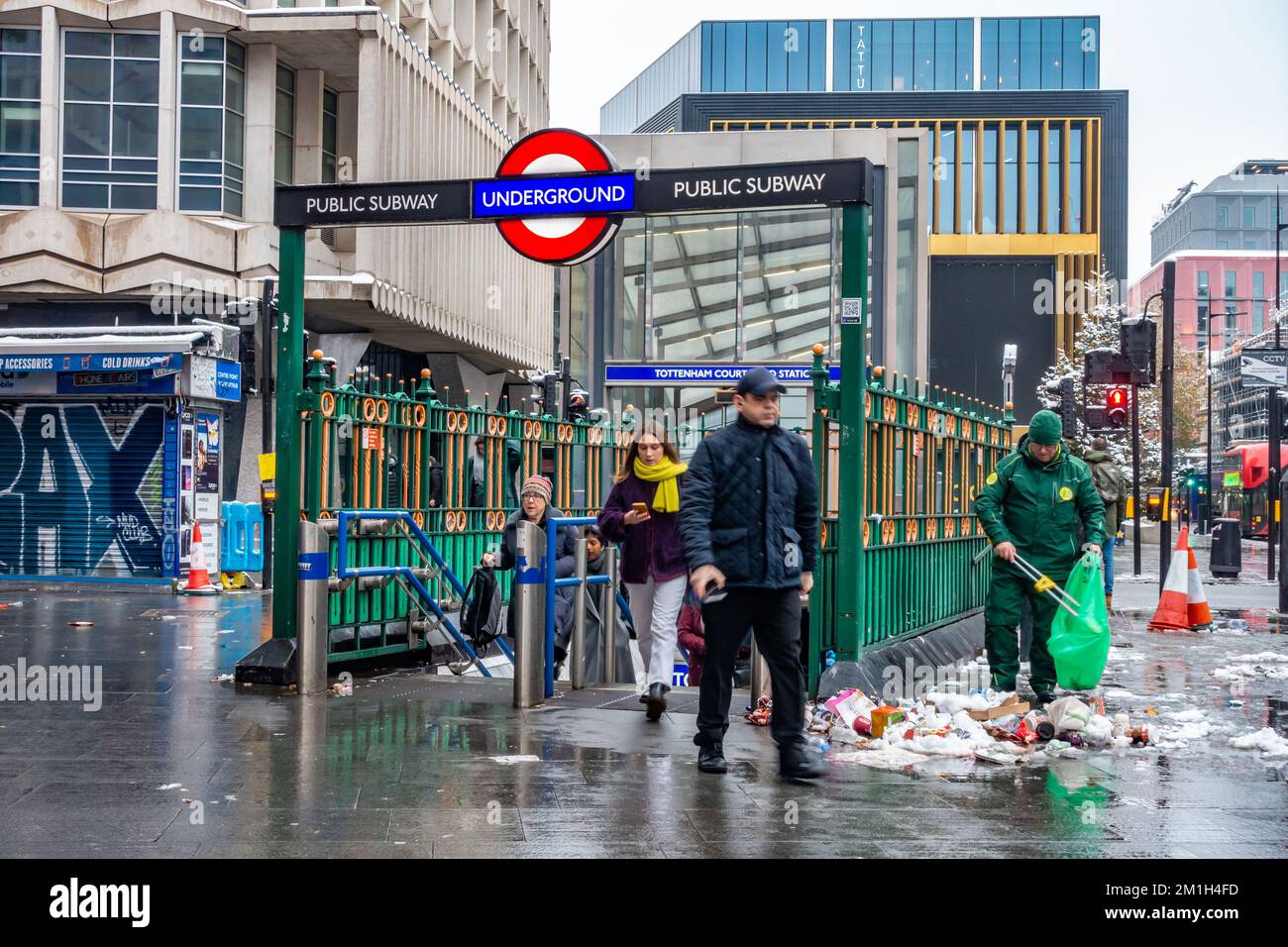 A street cleaner picks up a large pile of rubbish next to an entrance to Tottenham Court Road London Underground Station. Stock Photo