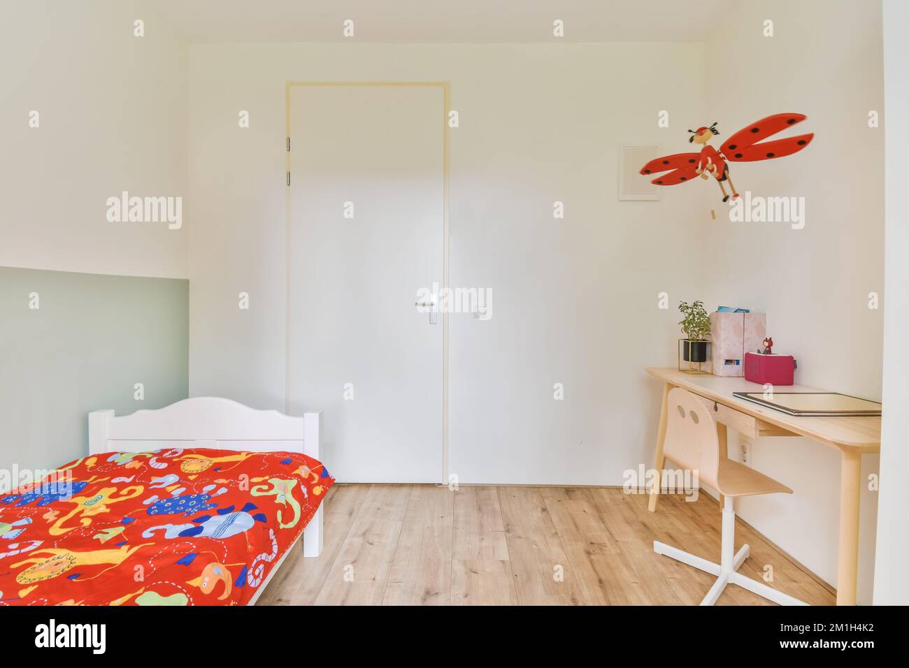 a child's room with a bed, desk and toy plane hanging on the wall above it in an apartment Stock Photo