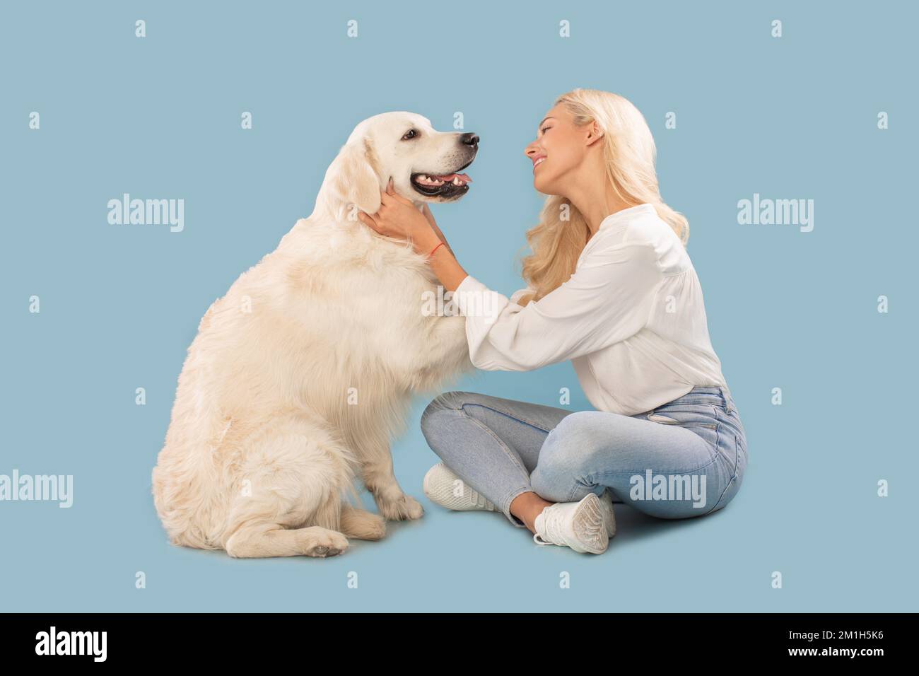 Loving caucasian woman carrying her sweet fluffy golden retriever