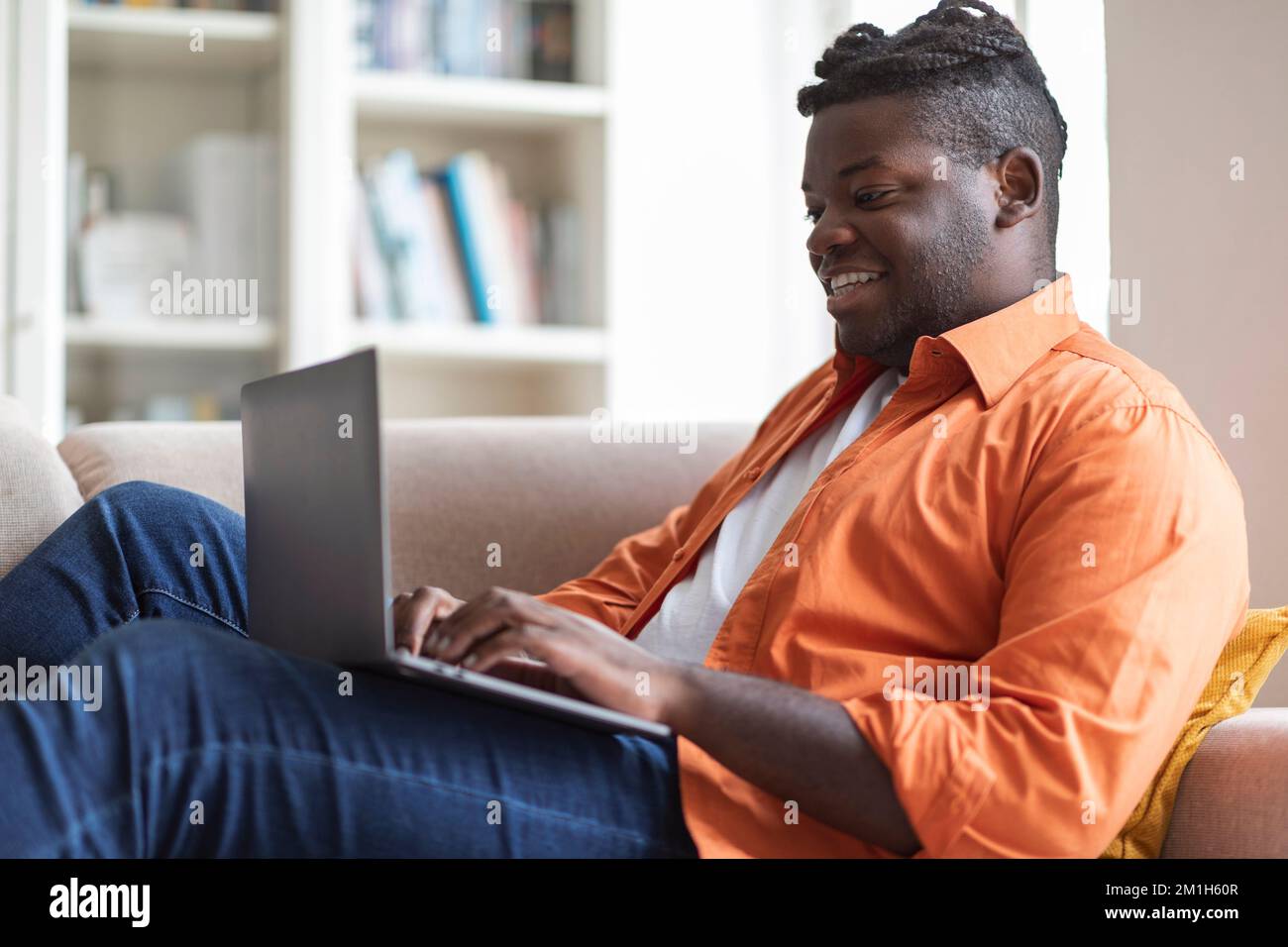 Happy Chubby Black Guy Using Laptop at Home Stock Photo