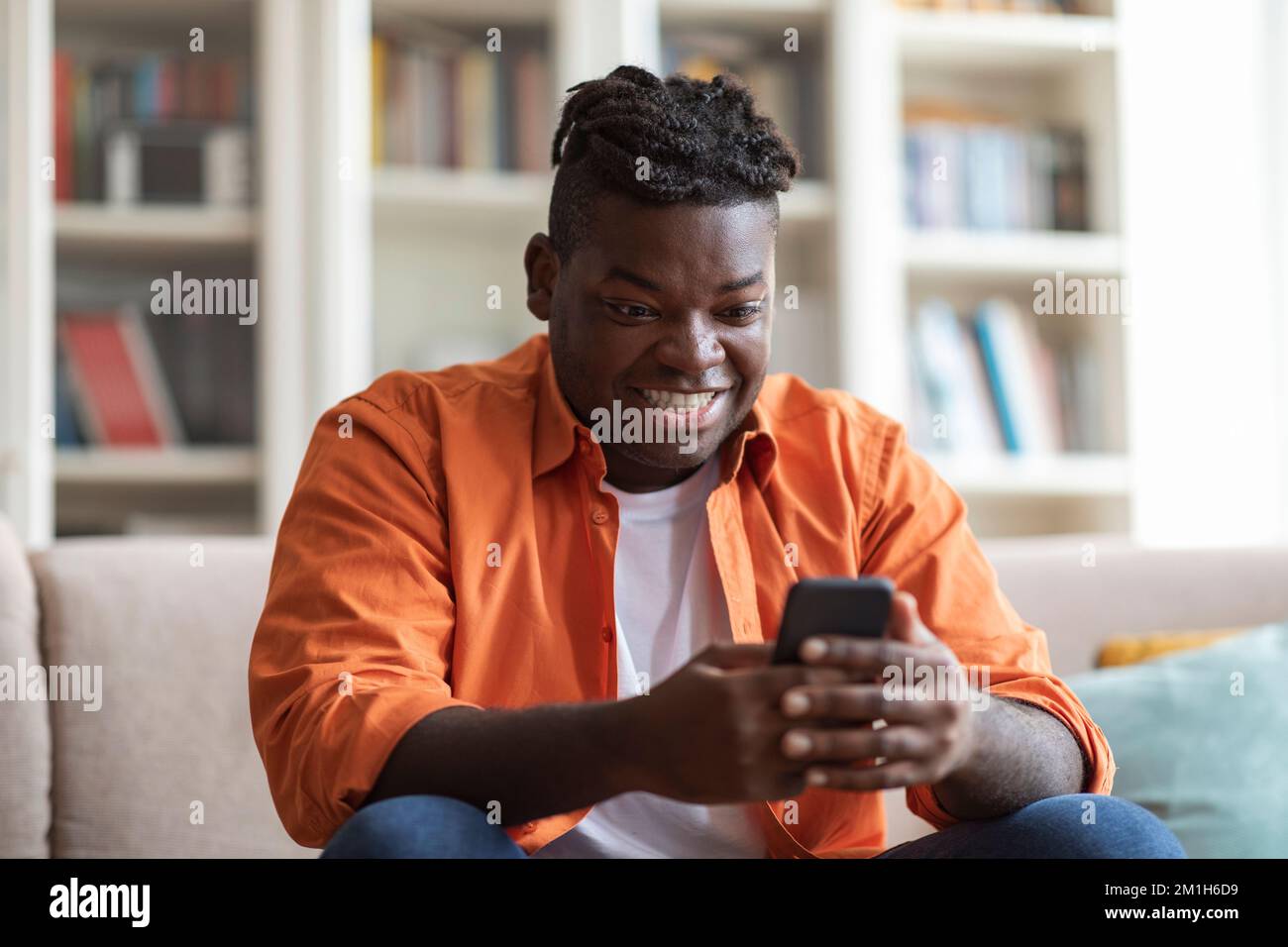 Smiling african american guy using cell phone at home Stock Photo