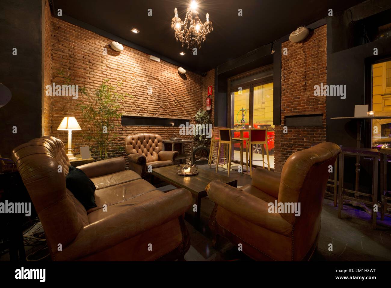 Recreation area of a bar with brown leather sofas and wooden and metal