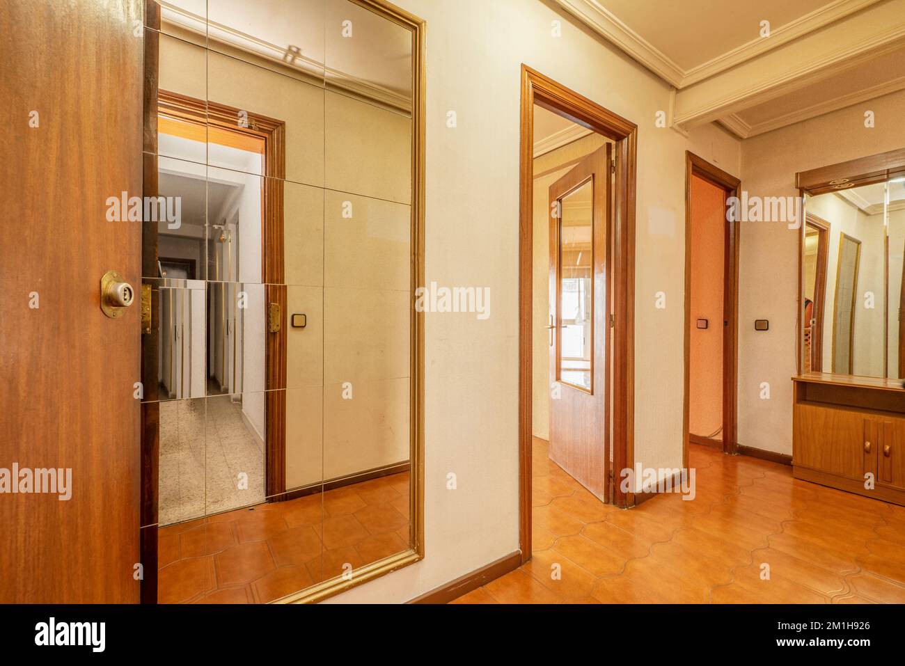 Entrance hall of a house with a fulllength mirror, ugly brown tiled