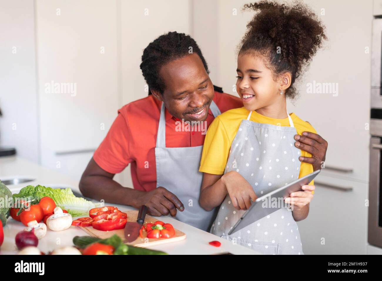 Black Father And Daughter Using Digital Tablet While Cooking In Kitchen ...