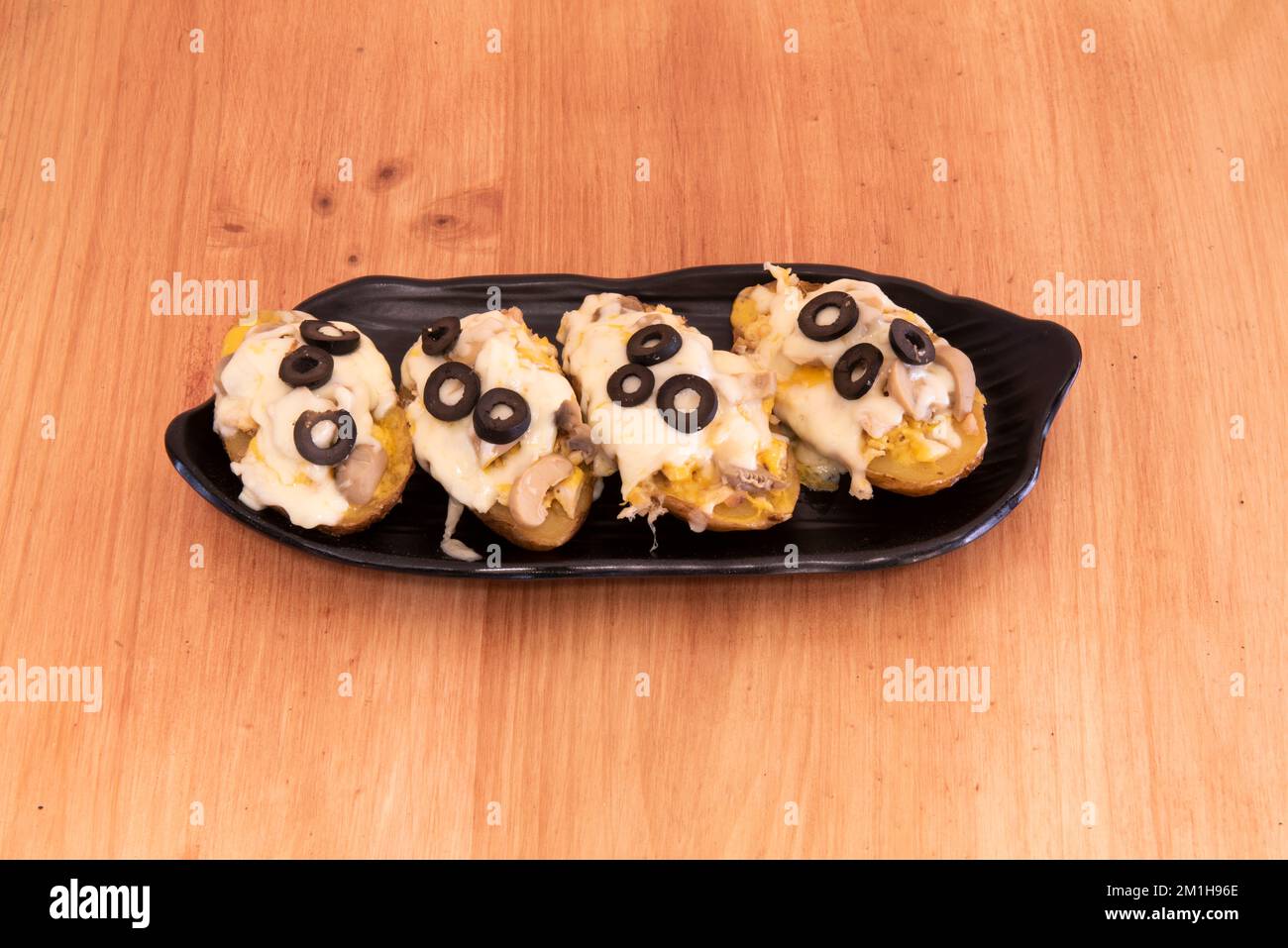 Roasted potatoes stuffed with mushrooms, black olives and melted cheese Stock Photo Alamy