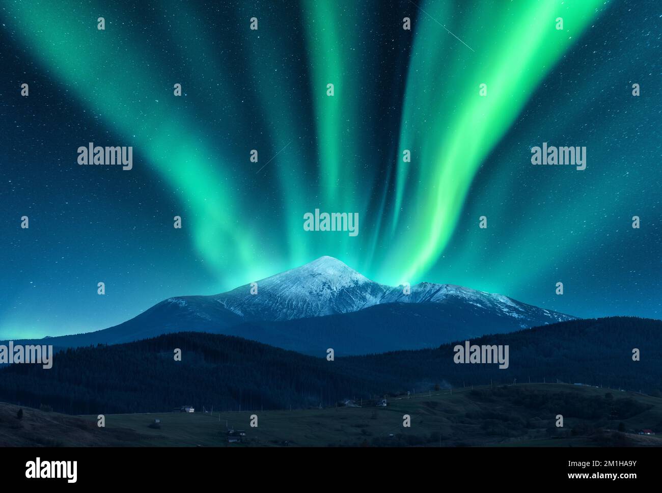 Aurora borealis over the snow covered mountain peak Stock Photo