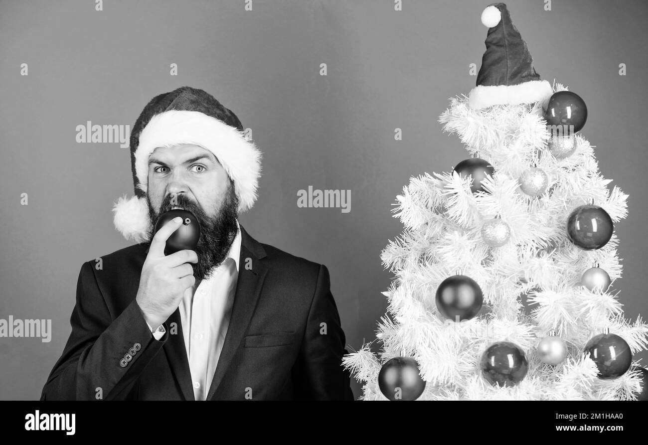 Feeling hungry. Santa bearded man biting red christmas ball. Hungry
