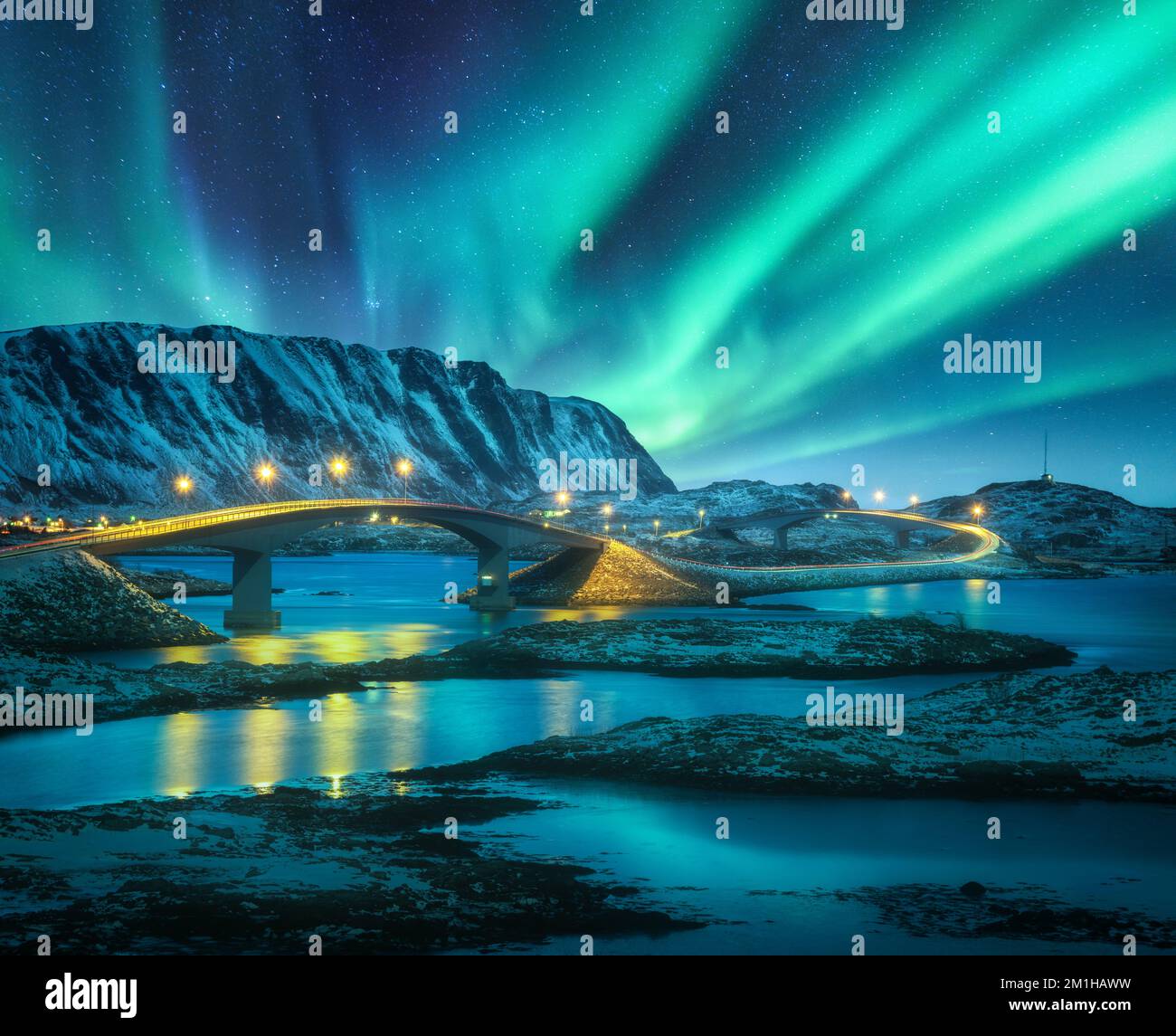 Bridge and northern lights over snowy mountains. Lofoten islands Stock