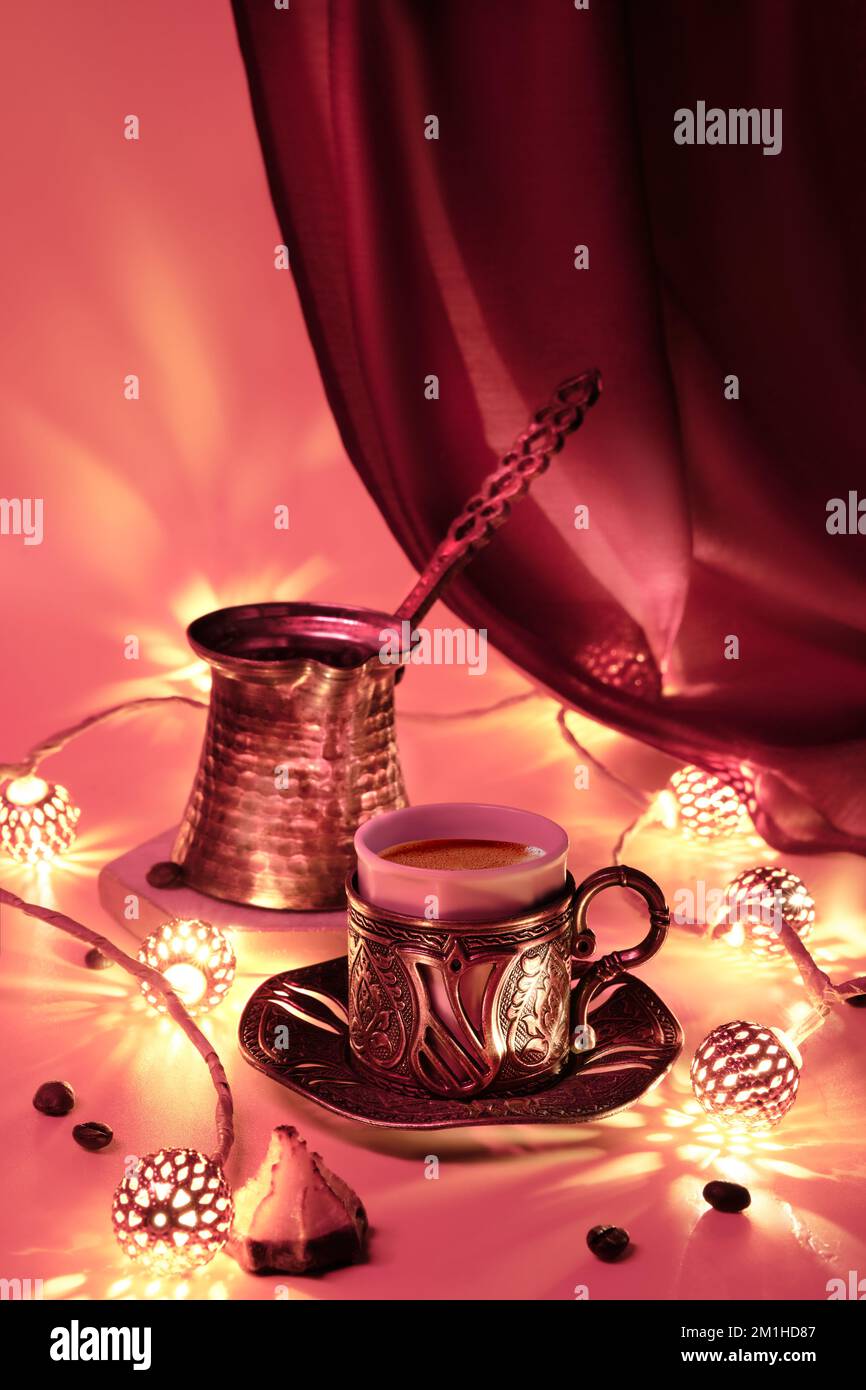 Turkish coffee pot and traditional cup with oriental sweets. Ornate copper metal garland and tea