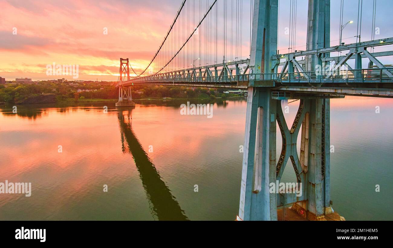 Pink and golden sunrise light behind stunning American bridge on Hudson River Stock Photo