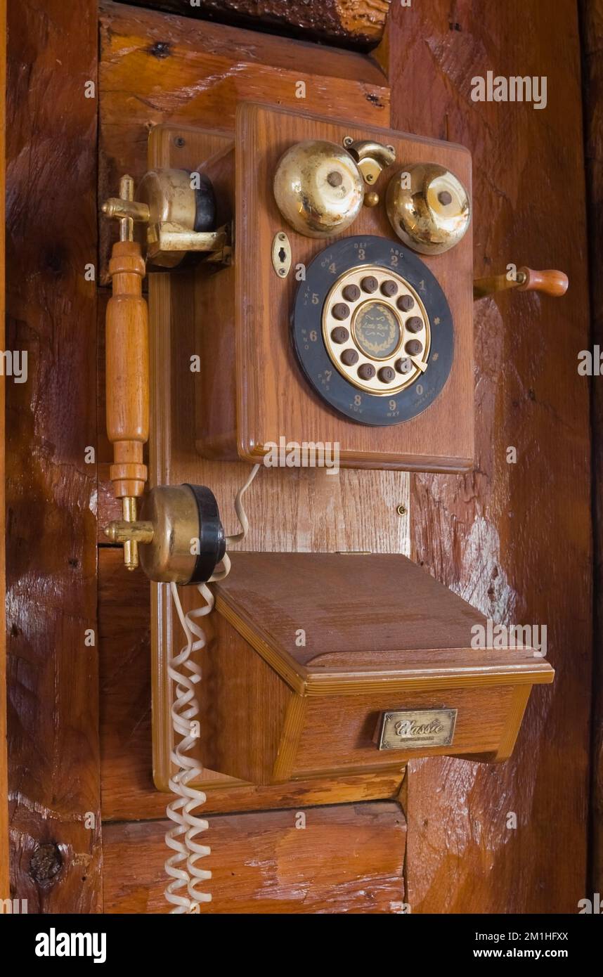 Antique wall mounted telephone on wall in hallway inside old 1800s Canadiana log home. Stock Photo