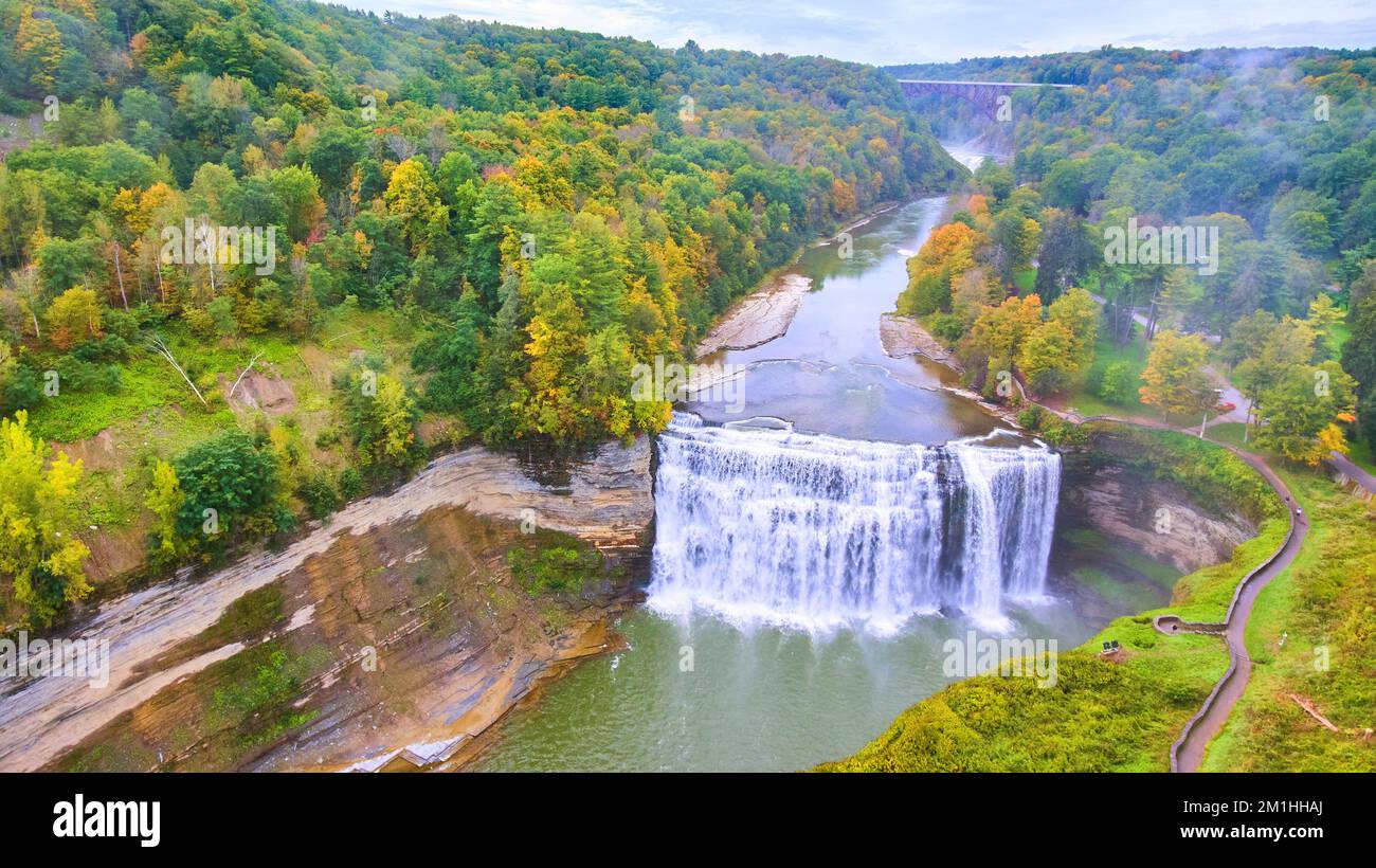 Aerial above huge waterfall in canyon during early fall with train