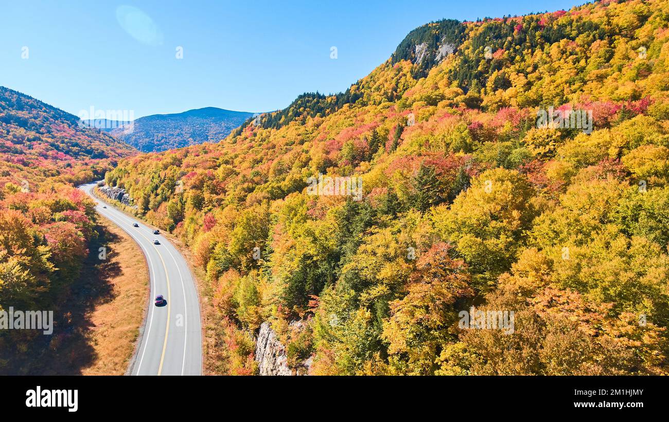 Aerial view of road tucked into New Hampshire mountains covered in peak