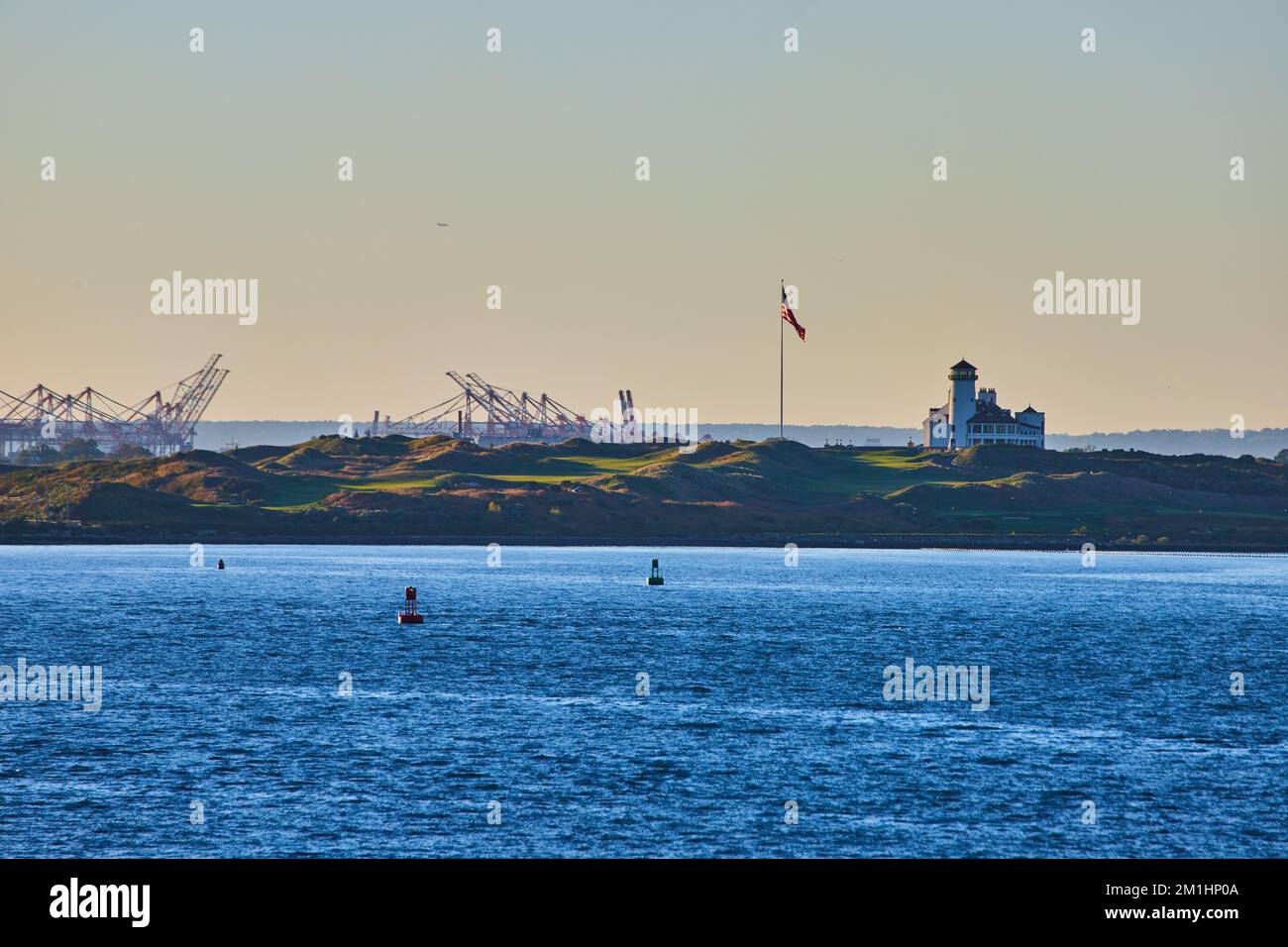 Bayonne Golf Country Club in New York City from waters with industrial structures and American flag during soft sunset Stock Photo