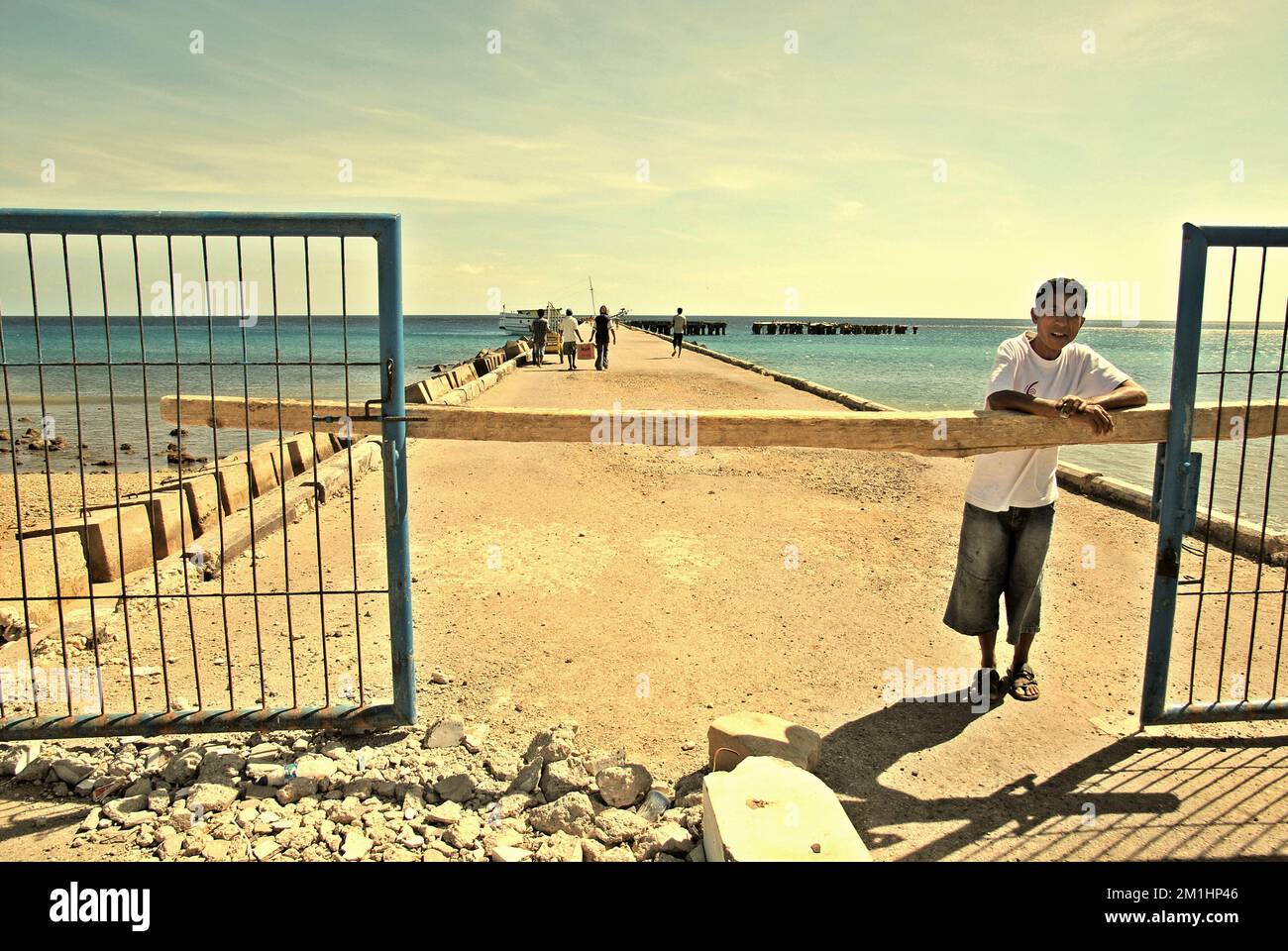 A man is photographed at the gate of ferry harbour in Baa, Central Rote, Rote Ndao, East Nusa Tenggara, Indonesia. A publication on World Bank website, published on July 18, 2018, analyzed that low transport infrastructure performance and capacity is one of the most critical barriers hindering Indonesia’s competitiveness and fueling social inequality across the archipelago. Indonesia ranked only 63rd in the 2016 Logistics Performance Index, as mentioned by Tomas Herrero Diez, the writer. Stock Photo