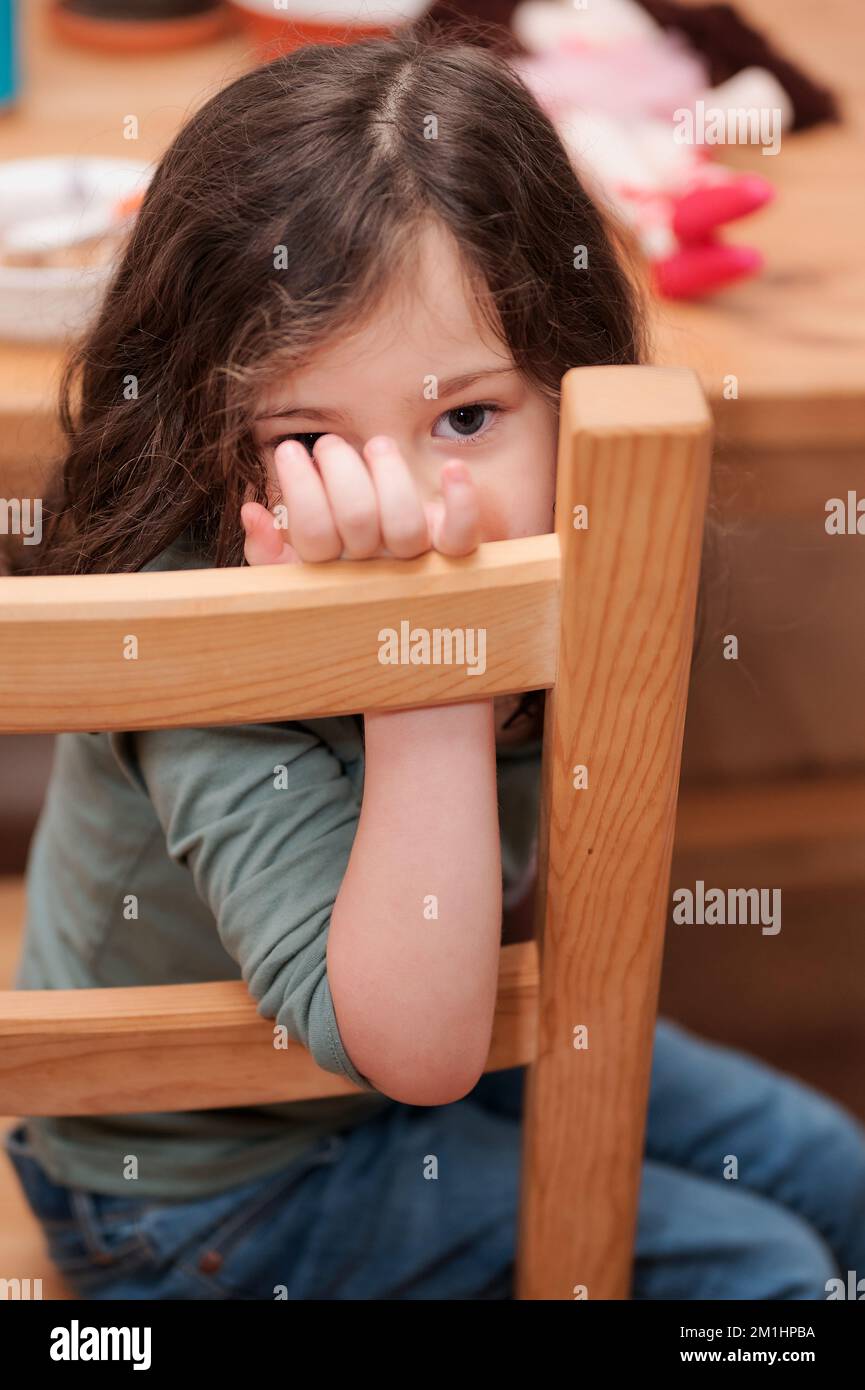 cute little girl making faces for the camera while sitting at a table Stock Photo