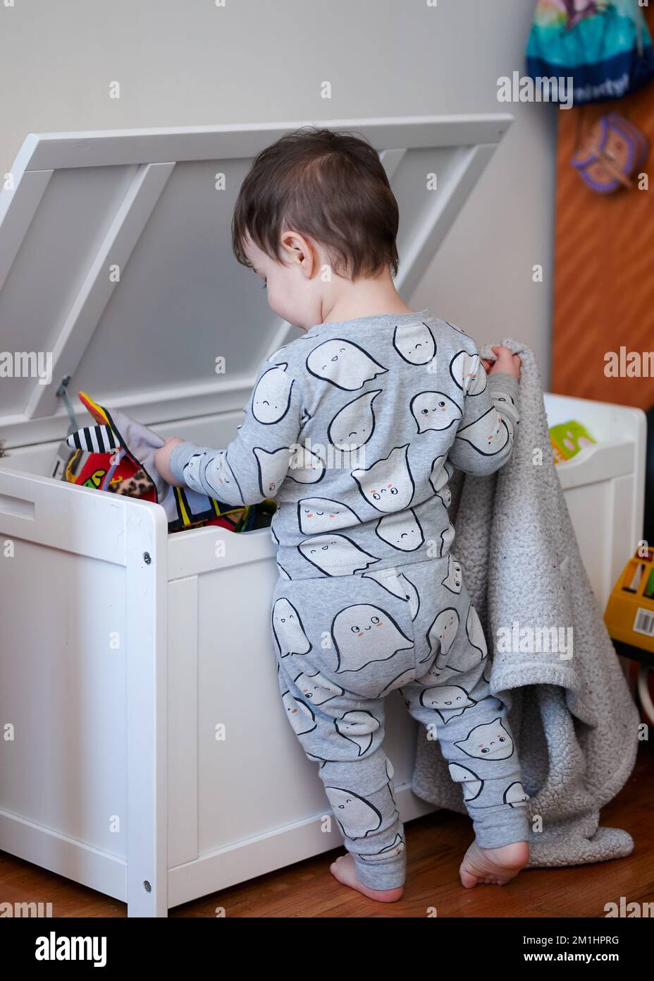cute little boy throwing toys out of the toy box while sitting inside