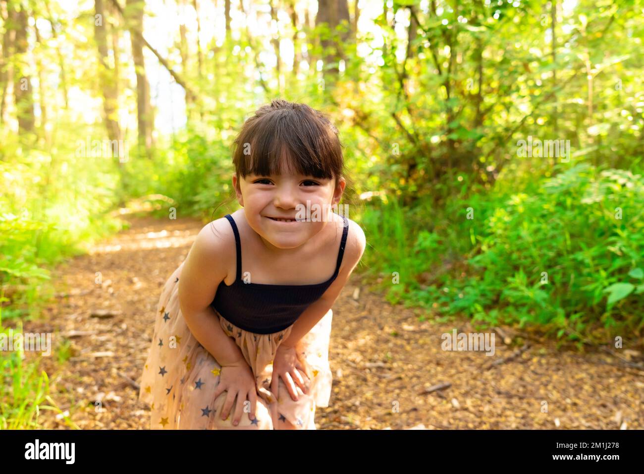 Cute little girl having fun during a walk in the woods on a beautiful spring day. Active family leisure with children. Stock Photo