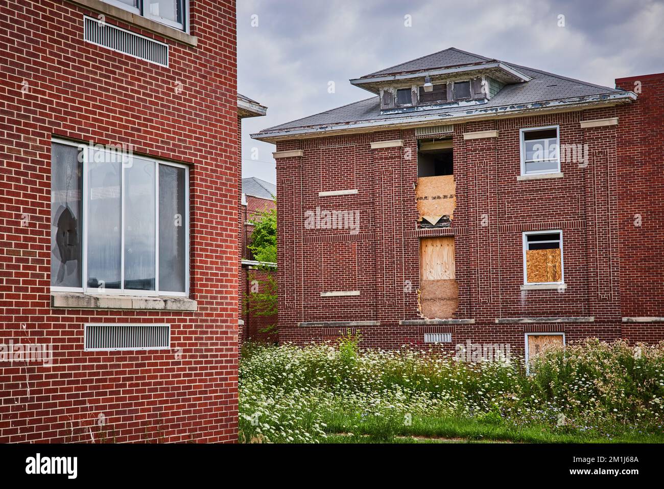 Abandoned brick buildings in fields with boarded up windows Stock Photo