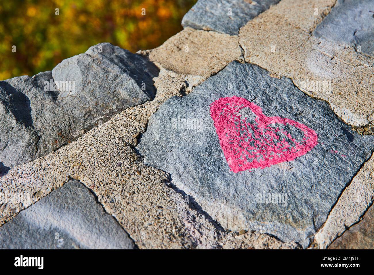 Stone wall detail of pink heart graffiti Stock Photo