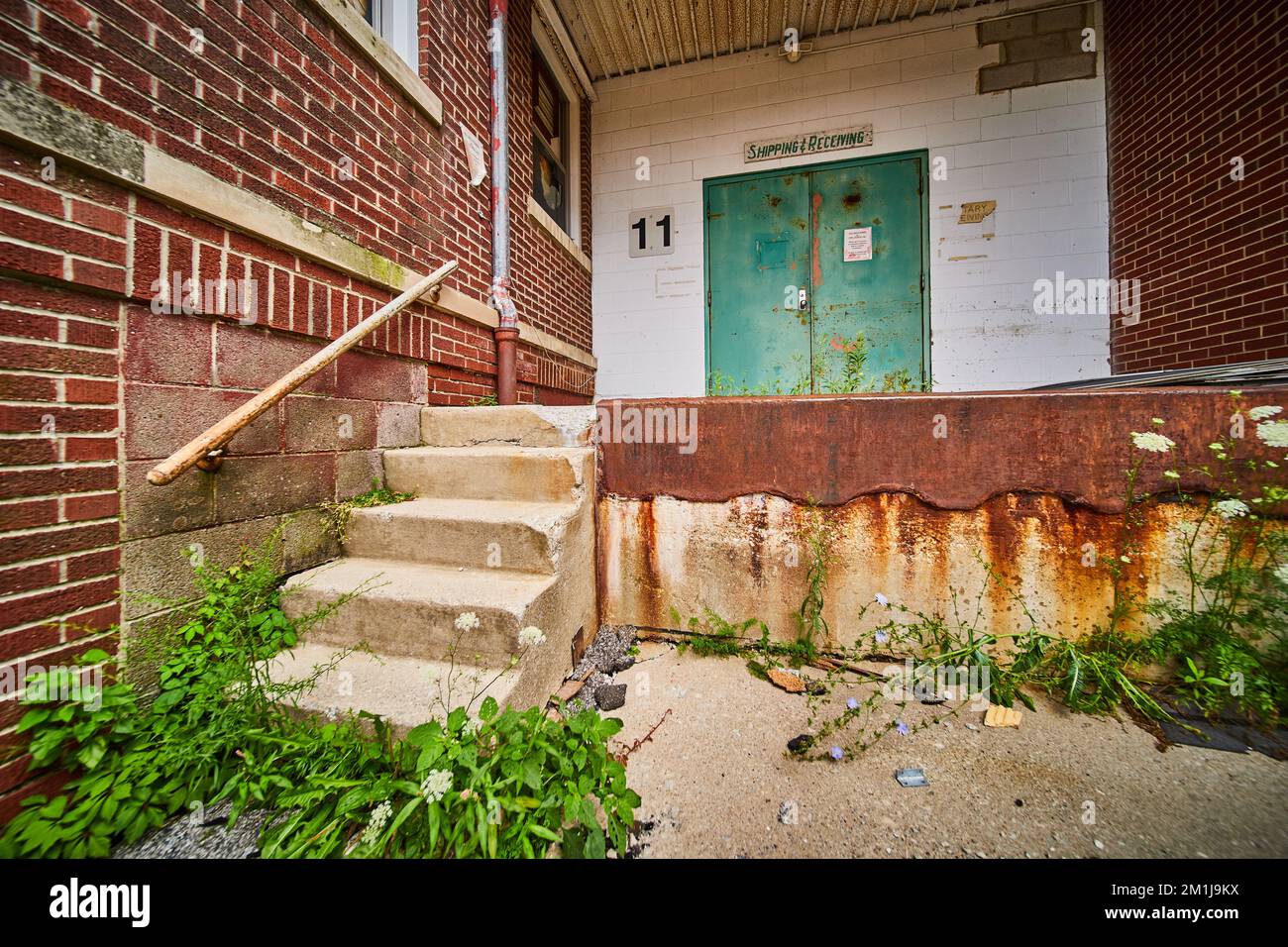 Abandoned building back shipping receiving entrance with brick, rust, and cement steps Stock Photo