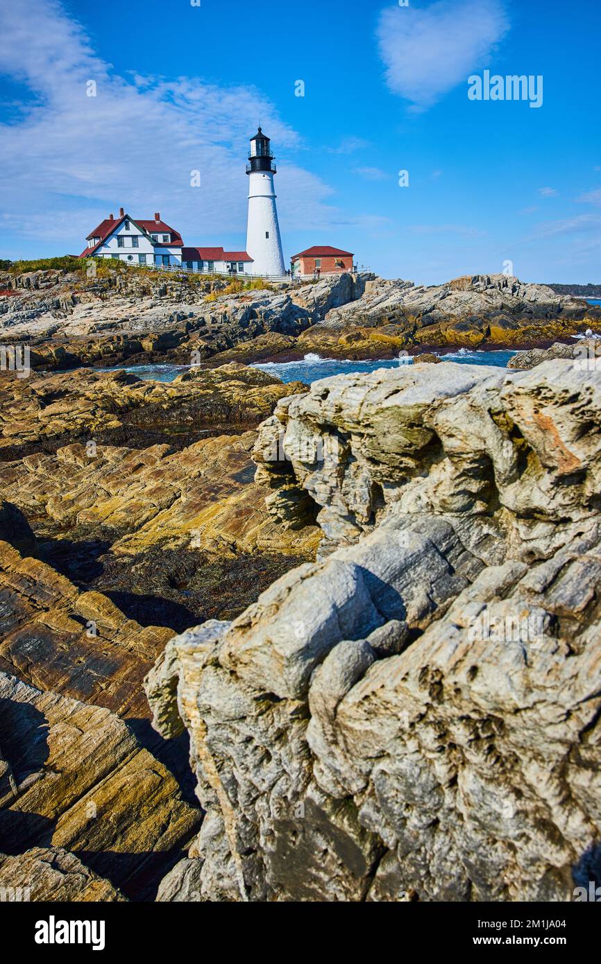 Lighthouse By Rocks Rocks like petrified wood with white lighthouse and rocky coastline in ...