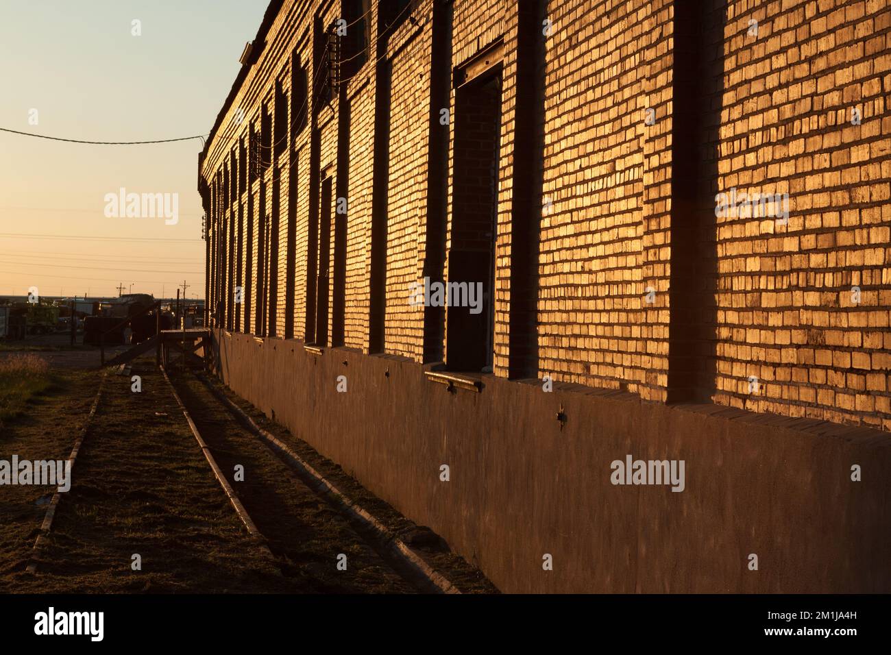 Side of old warehouse next to a railroad siding in Lamar, Colorado, just after sunrise Stock Photo