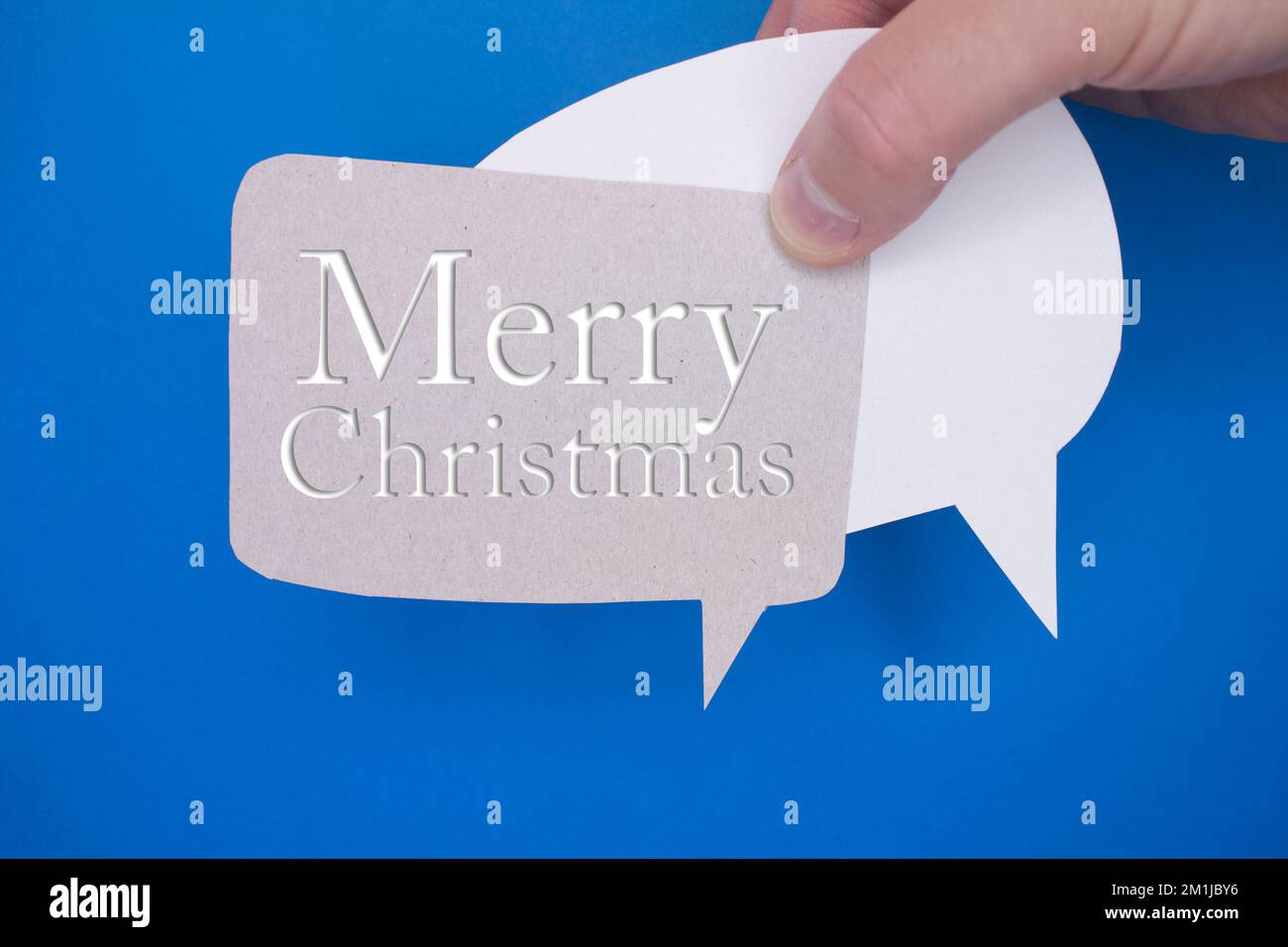 Speech bubble in front of colored background with Merry Christmas text. Stock Photo