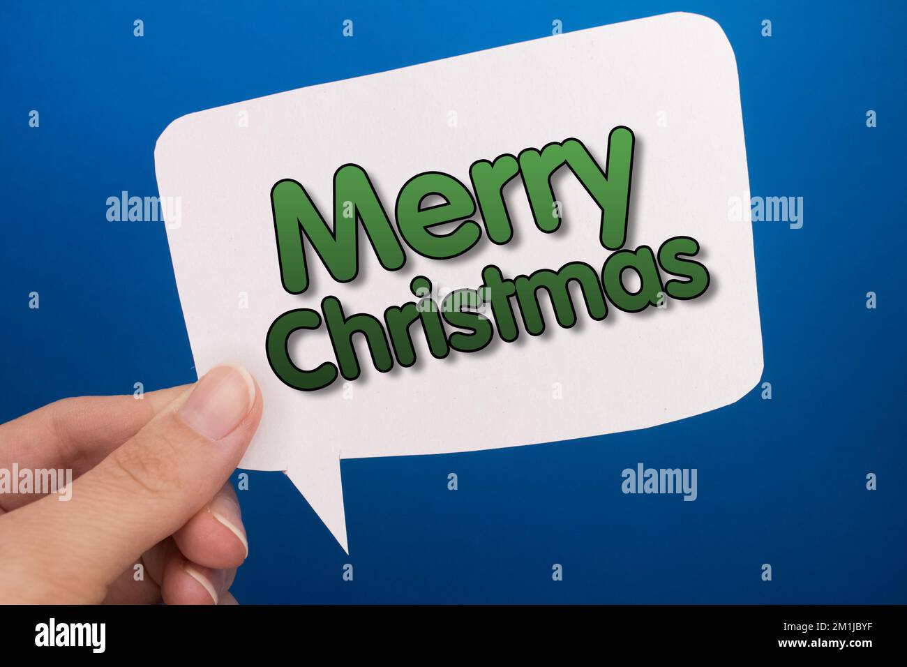 Speech bubble in front of colored background with Merry Christmas text. Stock Photo