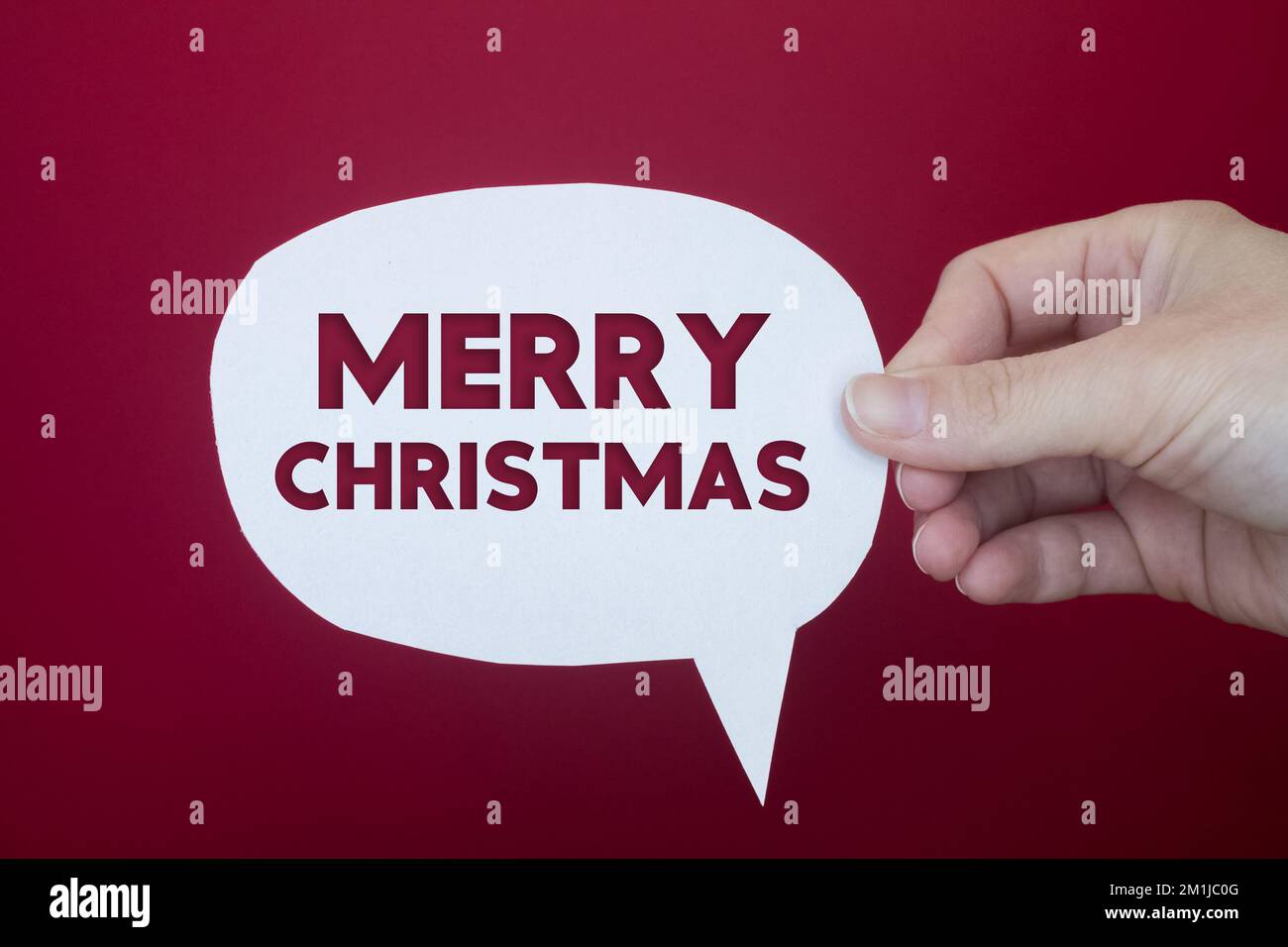 Speech bubble in front of colored background with Merry Christmas text. Stock Photo