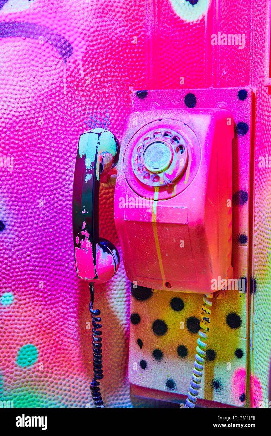 Detail of phone on phone booth painted in pink glowing graffiti Stock Photo