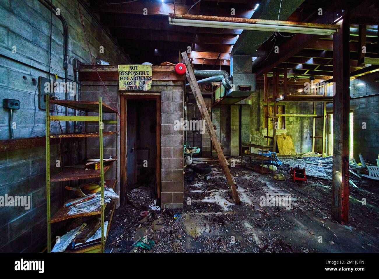 Interior abandoned mechanic shop with rubble and destroyed bathroom Stock Photo