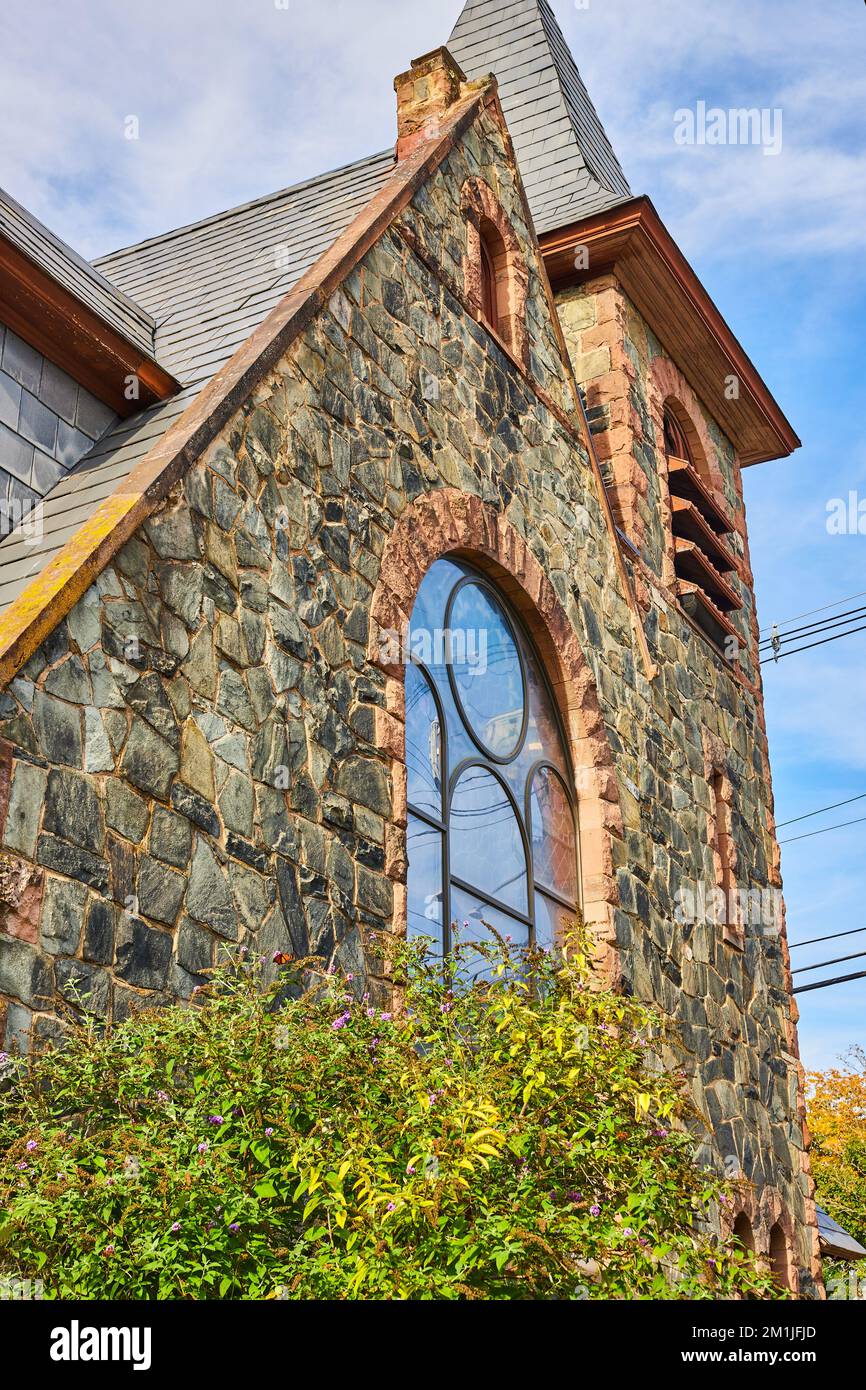 Looking up side of stone church in small town with glass window and ...